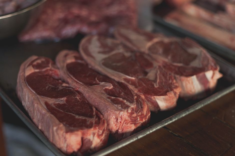 Three beef steaks with visibly different marbling arranged beside USDA-style grade cards on a cutting board.